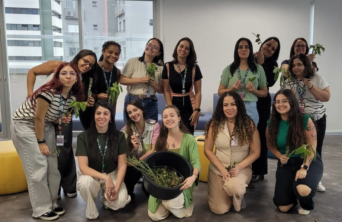 Equipe reunida no escritório segurando mudas e plantas ao final da oficina